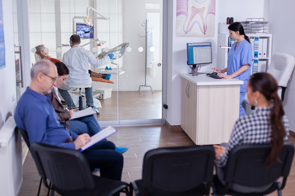 crowded stomatology waiting area with people filling form